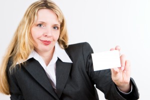 A blond business woman in a suit holding a blank business card